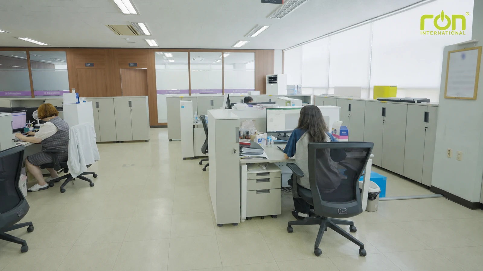 Nhân viên ngồi làm việc tại các bàn máy tính trong văn phòng có tủ hồ sơ.