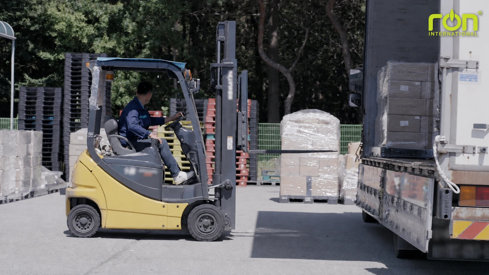 Người vận hành xe nâng bên xe tải và các pallet thùng hàng.