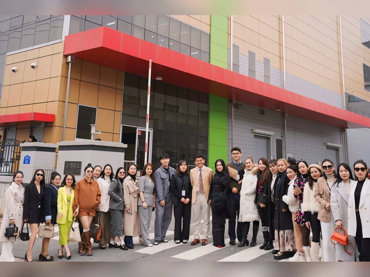 Nhóm người chụp ảnh trước tòa nhà có mái đón màu đỏ và cột màu xanh.