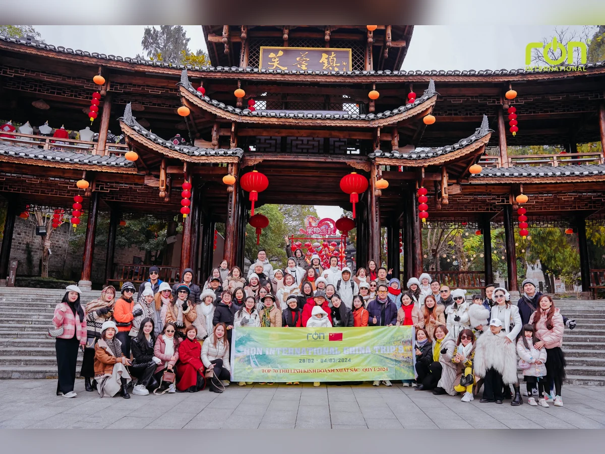 Đoàn người chụp ảnh cùng băng-rôn RON INTERNATIONAL China Trip 2024 trước cổng treo đèn lồng đỏ.