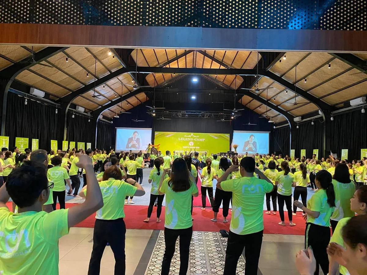 Nhóm người mặc áo xanh vàng có logo RON thực hiện động tác tay trước sân khấu LEGEND CAMP.