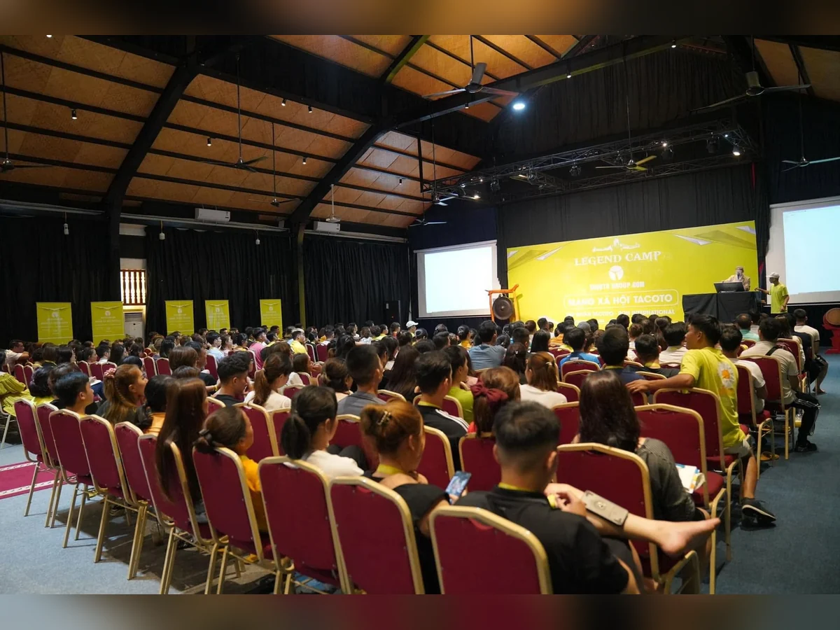 Người tham dự ngồi theo hàng hướng về sân khấu LEGEND CAMP và người đứng bên máy tính.
