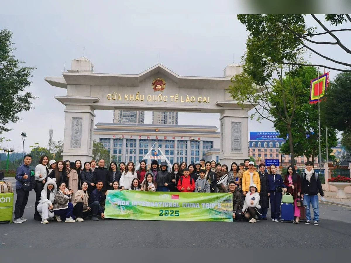 Đoàn người cầm băng rôn RON INTERNATIONAL CHINA TRIP 2025 trước cổng ghi CỬA KHẨU QUỐC TẾ LÀO CAI.