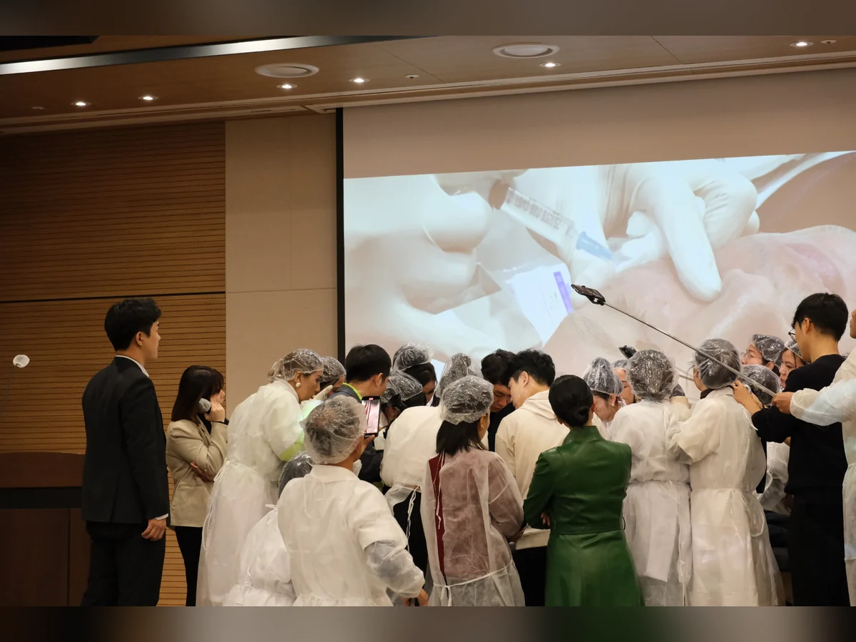 Nhóm người đứng quan sát và ghi hình trước màn chiếu cận cảnh thao tác trên da.